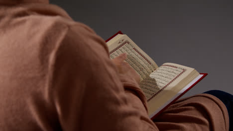 Close-Up-Of-Muslim-Woman-Sitting-On-Sofa-At-Home-Reading-Or-Studying-The-Quran-2